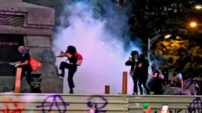 Protesta feminista con disturbios y humo en vía pública durante manifestación nocturna