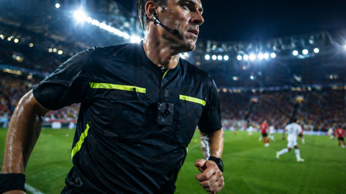 cámaras en árbitros fútbol durante partido con cámara corporal en el pecho en un estadio iluminado