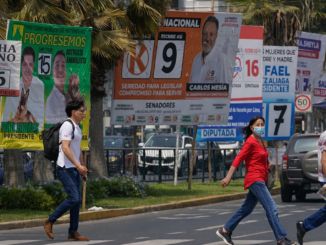 votantes caminando frente a propaganda electoral en Lima durante elecciones en Perú 2026