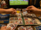 Álbum Panini Mundial abierto con estampas de selecciones y personas intercambiando cromos durante la Copa del Mundo
