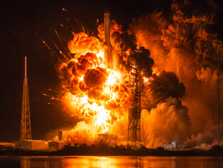 Explosión de un cohete durante una prueba o lanzamiento nocturno en una plataforma espacial, generando una enorme bola de fuego y columnas de humo.