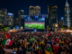 Fan zones 2026 con miles de aficionados viendo partidos del Mundial en pantallas gigantes durante la noche
