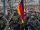 Rearme alemán con soldados portando bandera de Alemania durante despliegue militar en Berlín