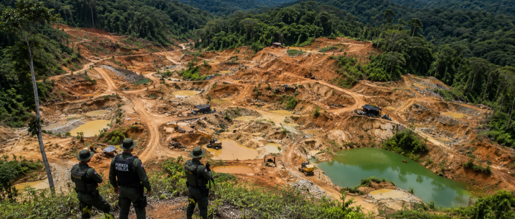 Vista aérea de Crucitas con extensas áreas afectadas por minería ilegal mientras oficiales observan la zona desde un punto elevado.