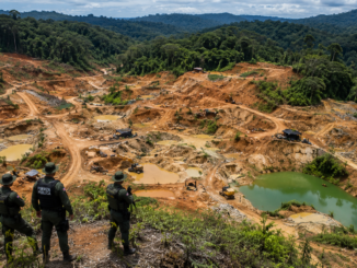 Vista aérea de Crucitas con extensas áreas afectadas por minería ilegal mientras oficiales observan la zona desde un punto elevado.