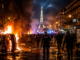 Policías antidisturbios avanzan entre vehículos incendiados durante los disturbios en París tras la victoria del PSG en la Champions League.