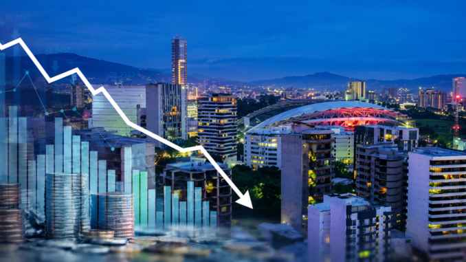 Vista panorámica de San José con gráficos financieros descendentes que representan la desaceleración económica y la contracción del mercado laboral en Costa Rica.
