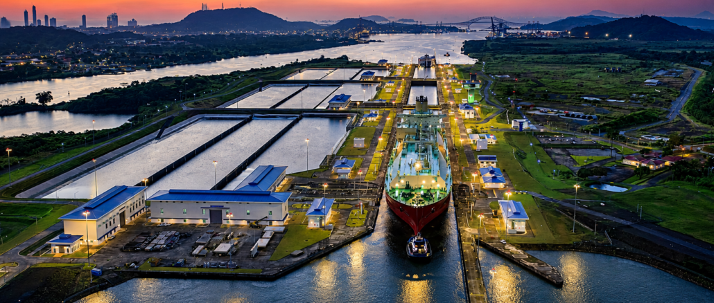 Vista aérea del Canal de Panamá con un buque atravesando una de sus esclusas al atardecer, una infraestructura clave para el comercio marítimo mundial.