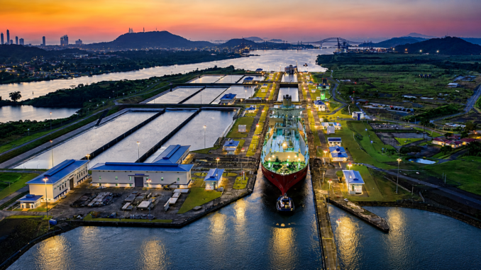Vista aérea del Canal de Panamá con un buque atravesando una de sus esclusas al atardecer, una infraestructura clave para el comercio marítimo mundial.